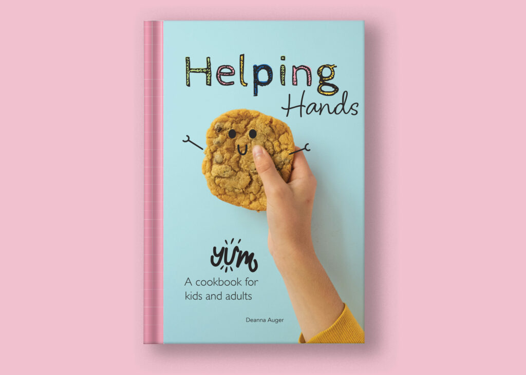 The cover of a cookbook for kids, child holding a cookie